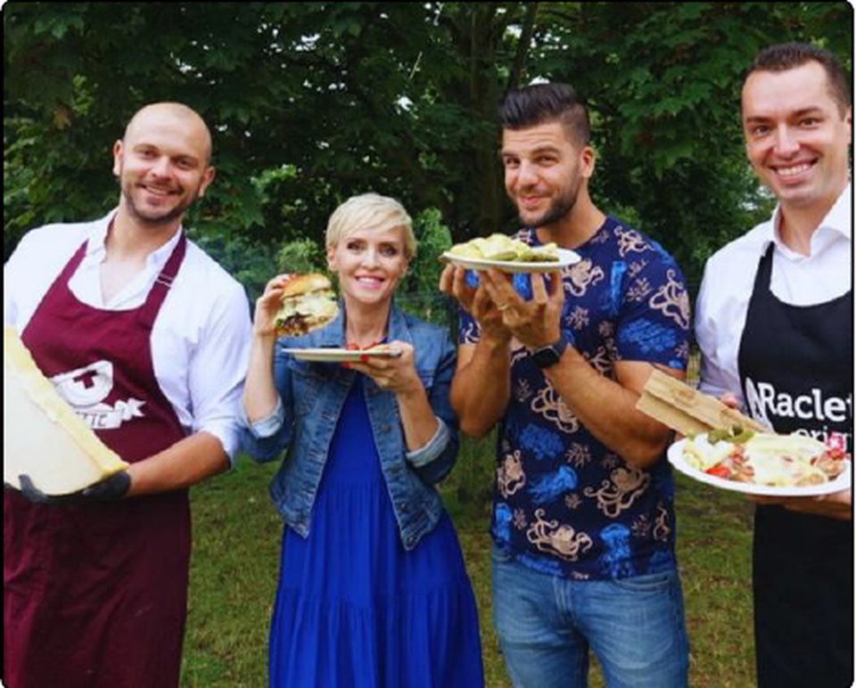 Groupe avec Milan Kolář et des invités avec des assiettes de raclette et des burgers à l'extérieur