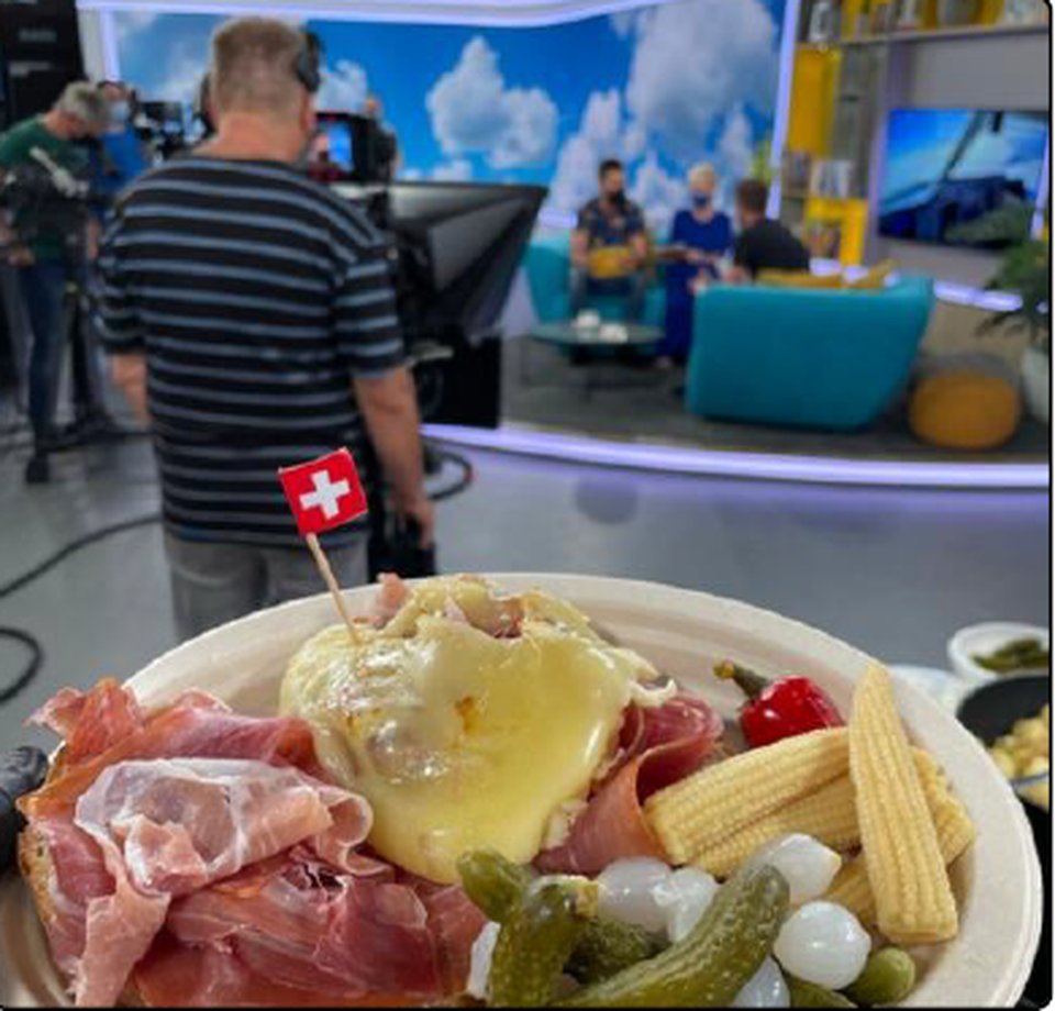 Une assiette de raclette avec un drapeau suisse dans un studio TV